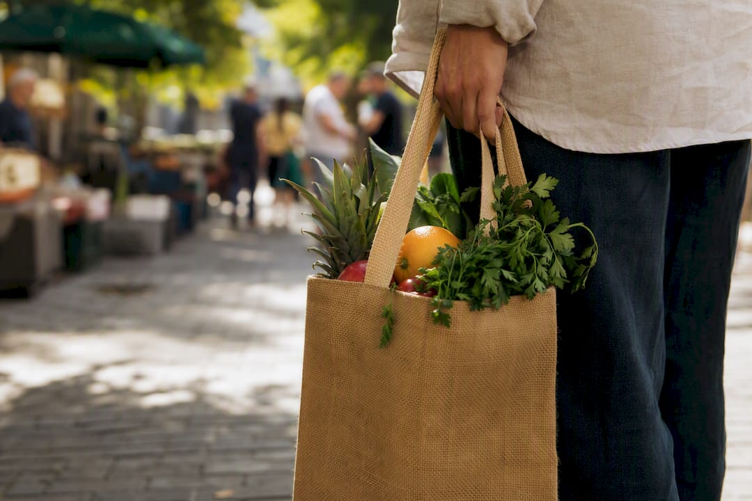Hand holding reusable shopping bag with vegetables