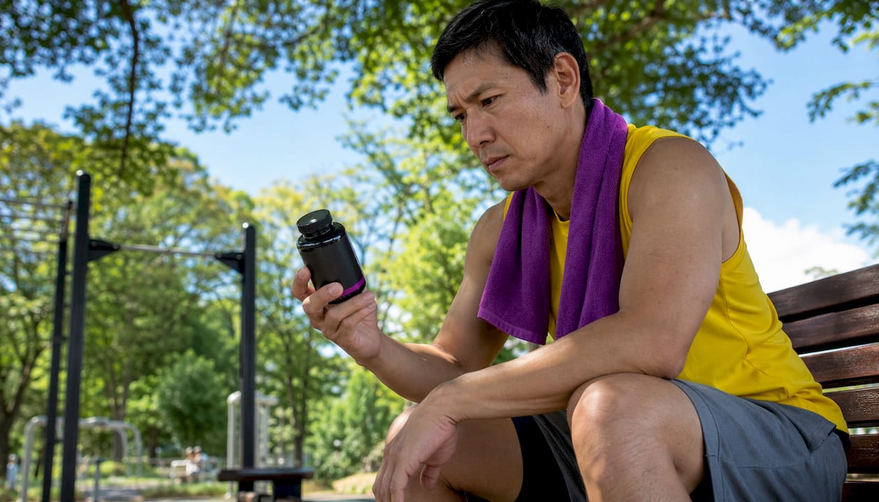 Athlete reading omega-3 supplement label in locker room