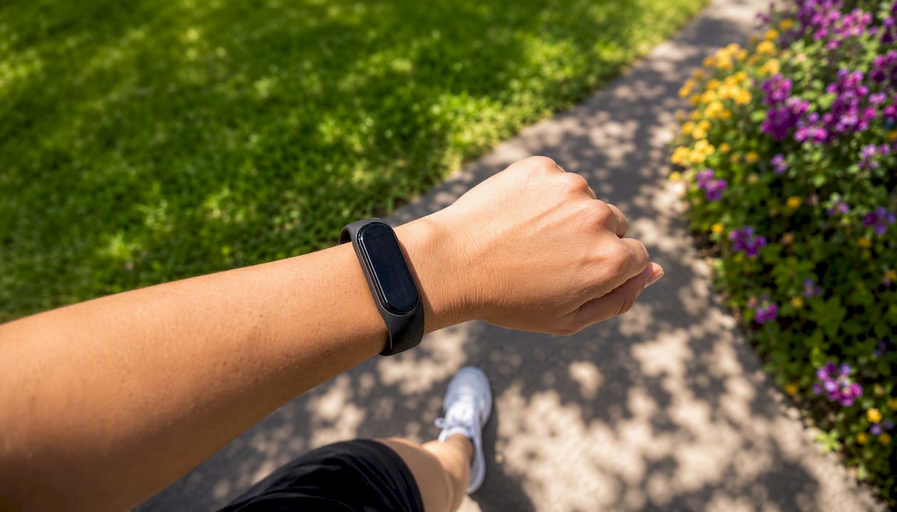Fitness tracker showing step count on wrist outdoors