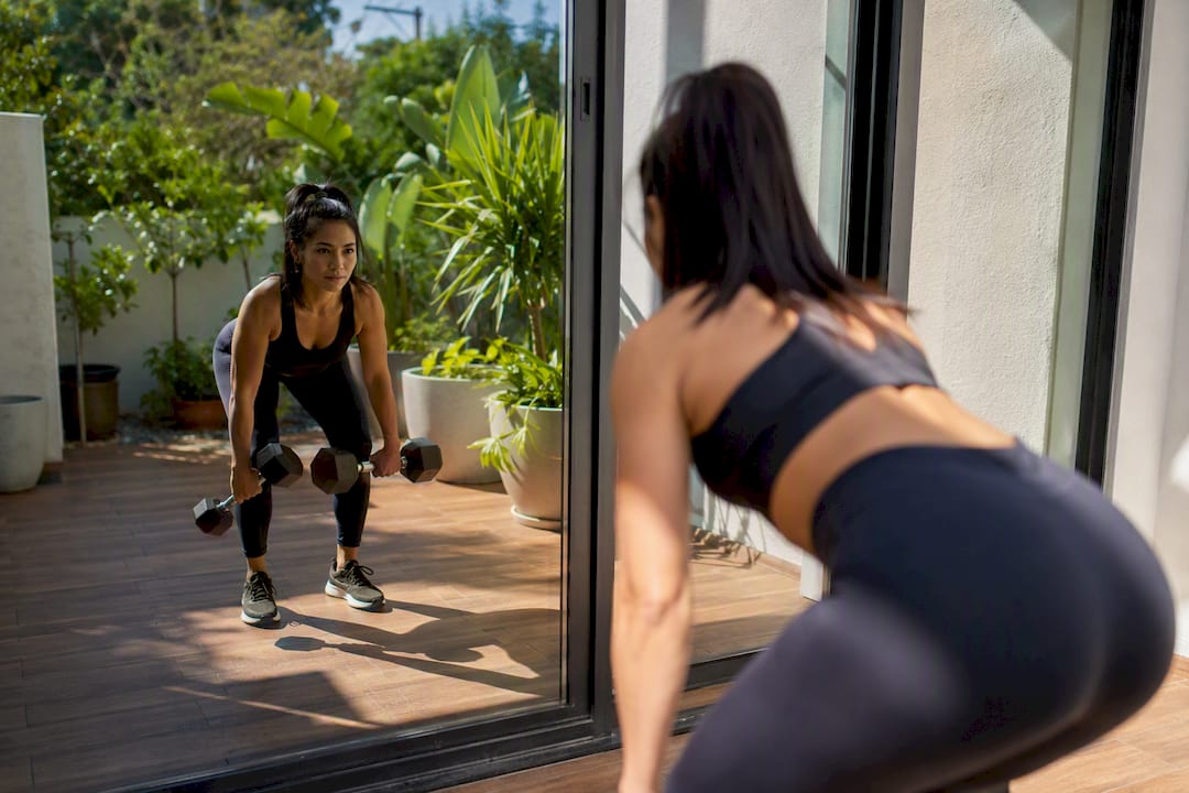Person monitoring dumbbell form in mirror