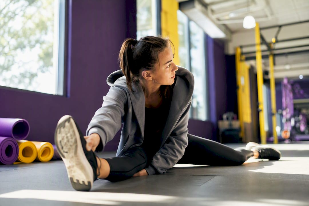 Person stretching post workout with hoodie on