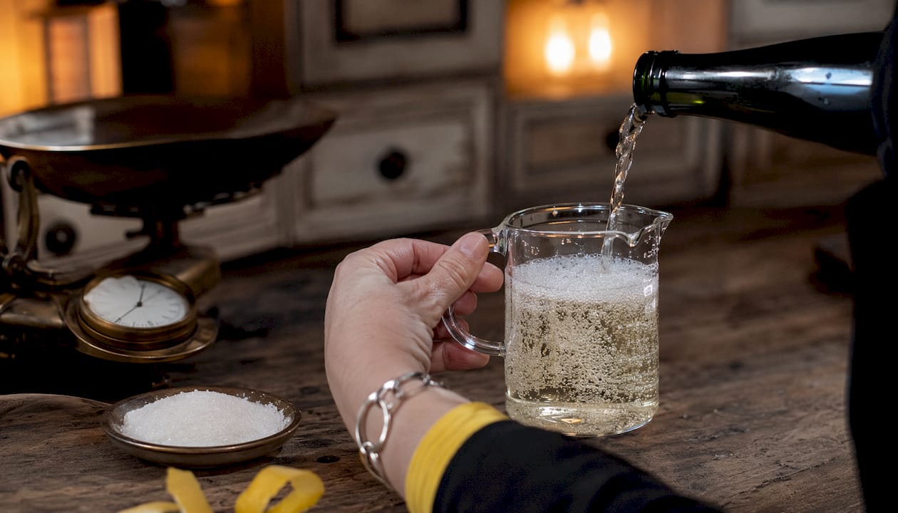 Close-up hand pouring Prosecco into measuring glass