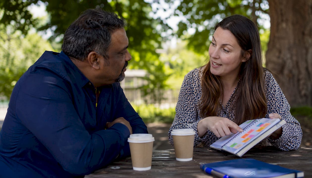 Man and woman discussing client outreach at café