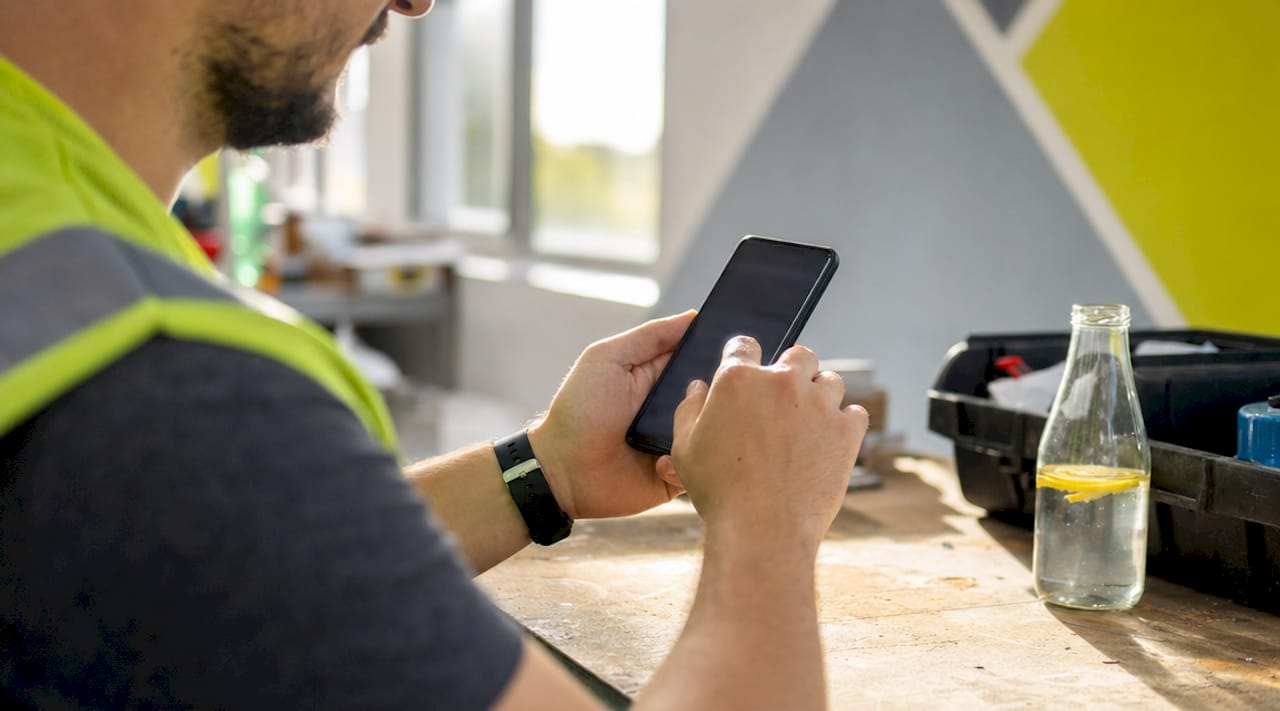 En anställd använder en mobilapp på jobbet i industrimiljö.