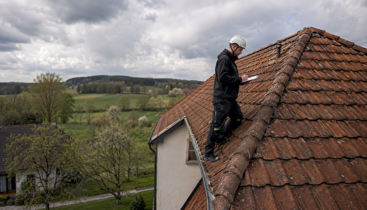Ein Fachmann überprüft das mit Ziegeln gedeckte Walmdach.