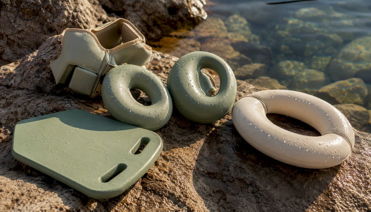 Am Beckenrand liegen verschiedene Schwimmhilfen und ein Schwimmbrett bereit.