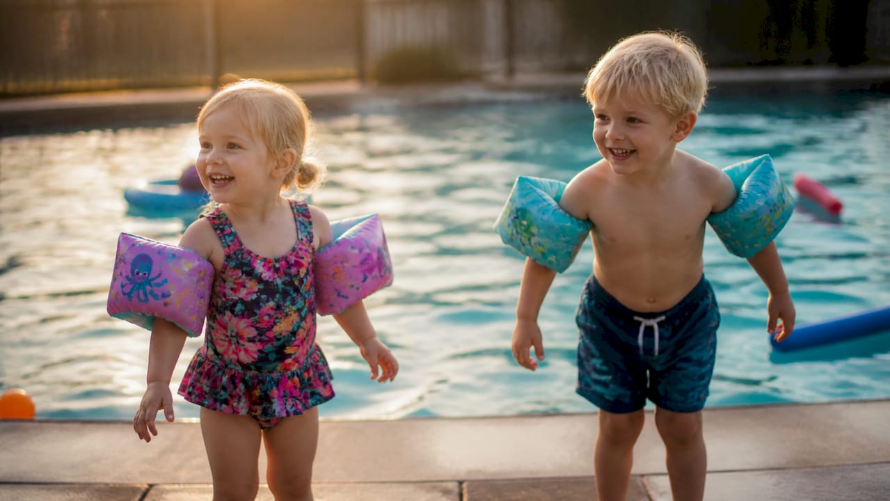 Kinder mit richtig angelegten Schwimmflügeln am Beckenrand