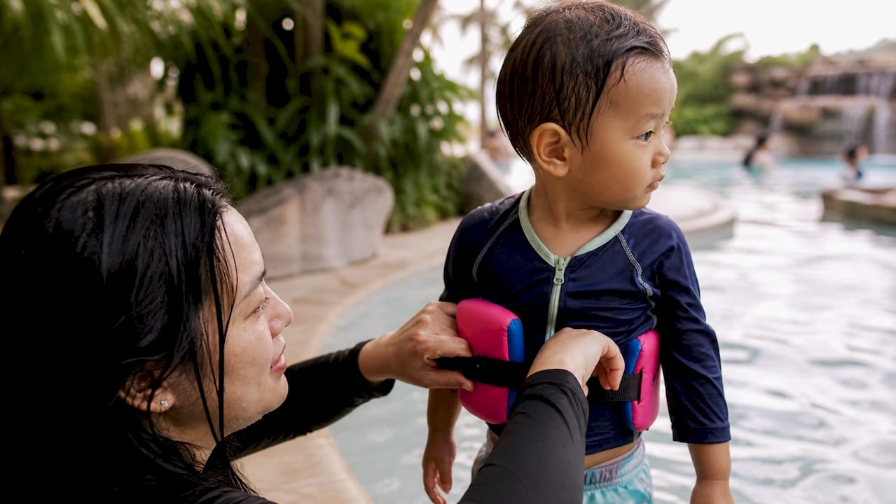 Eltern überprüfen, ob der Schwimmgürtel beim Kind richtig sitzt