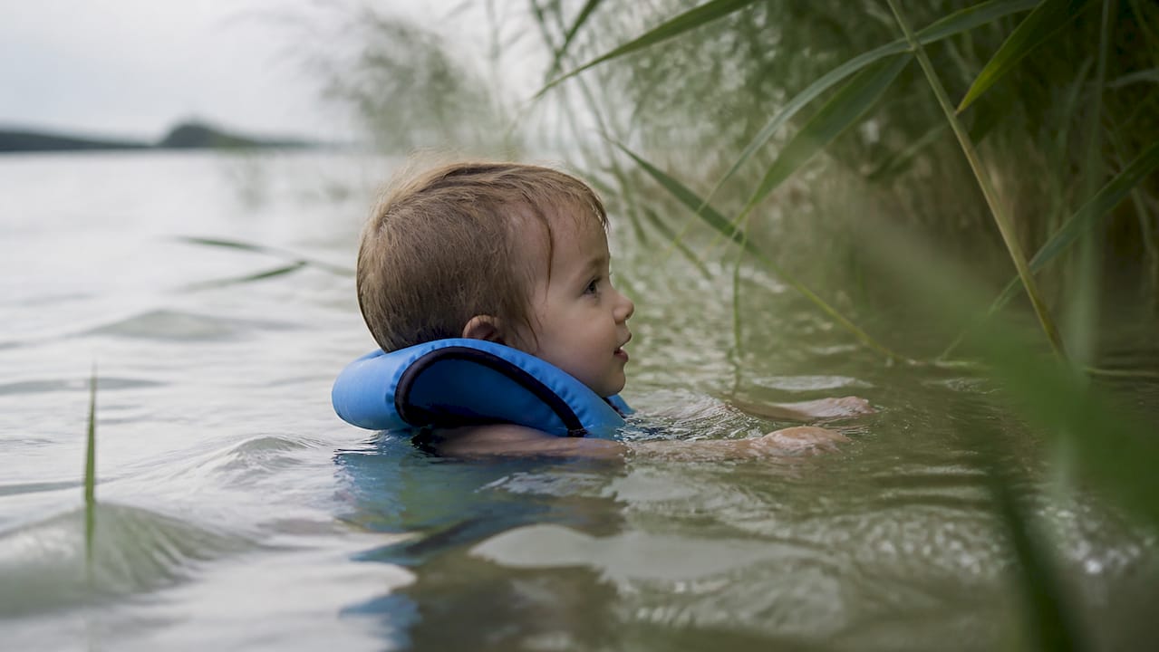 Kleinkind mit Schwimmweste seitlich im Wasser