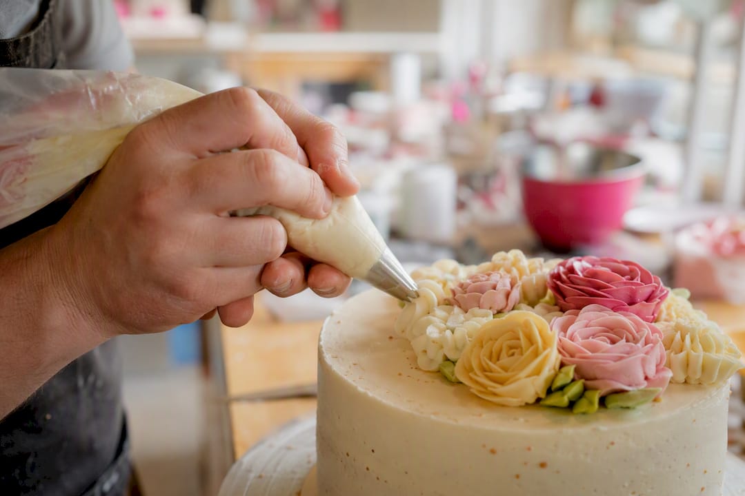 Mit einer russischen Tülle werden kunstvolle Verzierungen auf die Torte gespritzt.