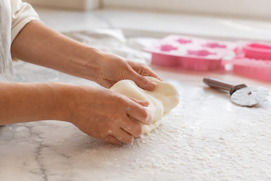 Hände beim Kneten von Rollfondant