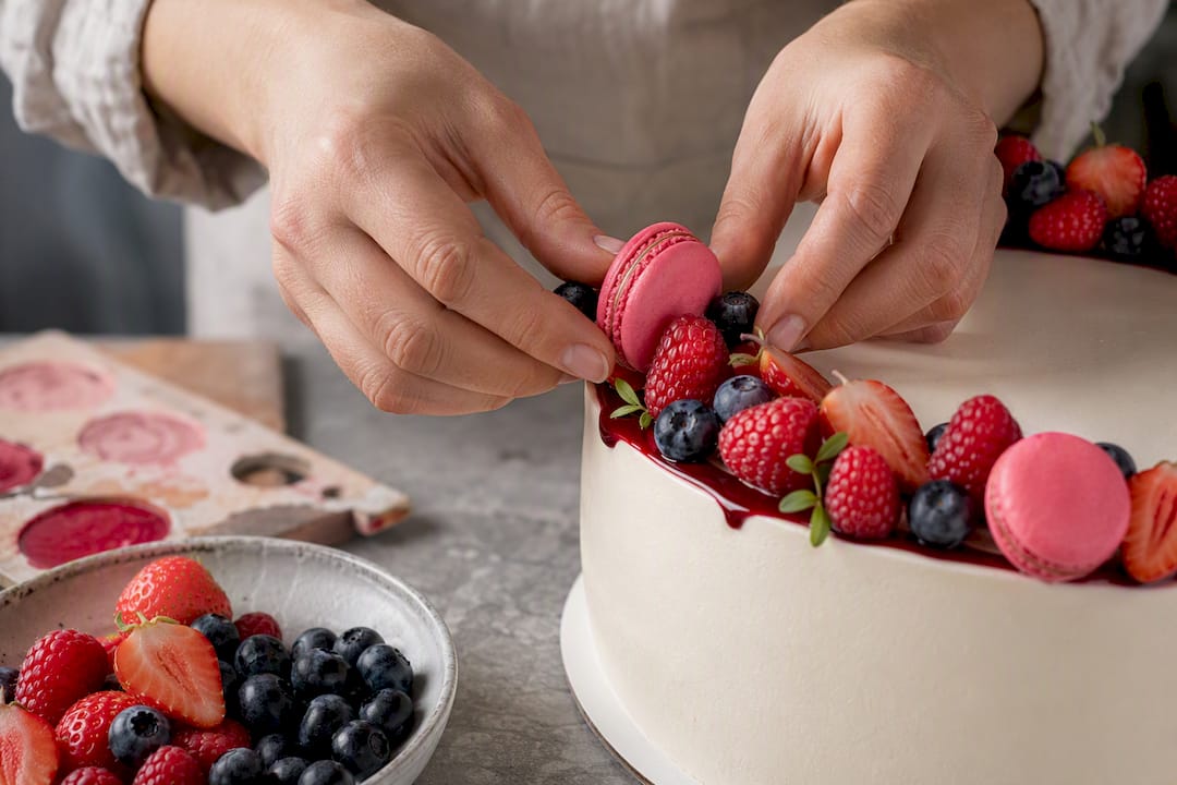Beeren und Macarons werden an der Torte befestigt
