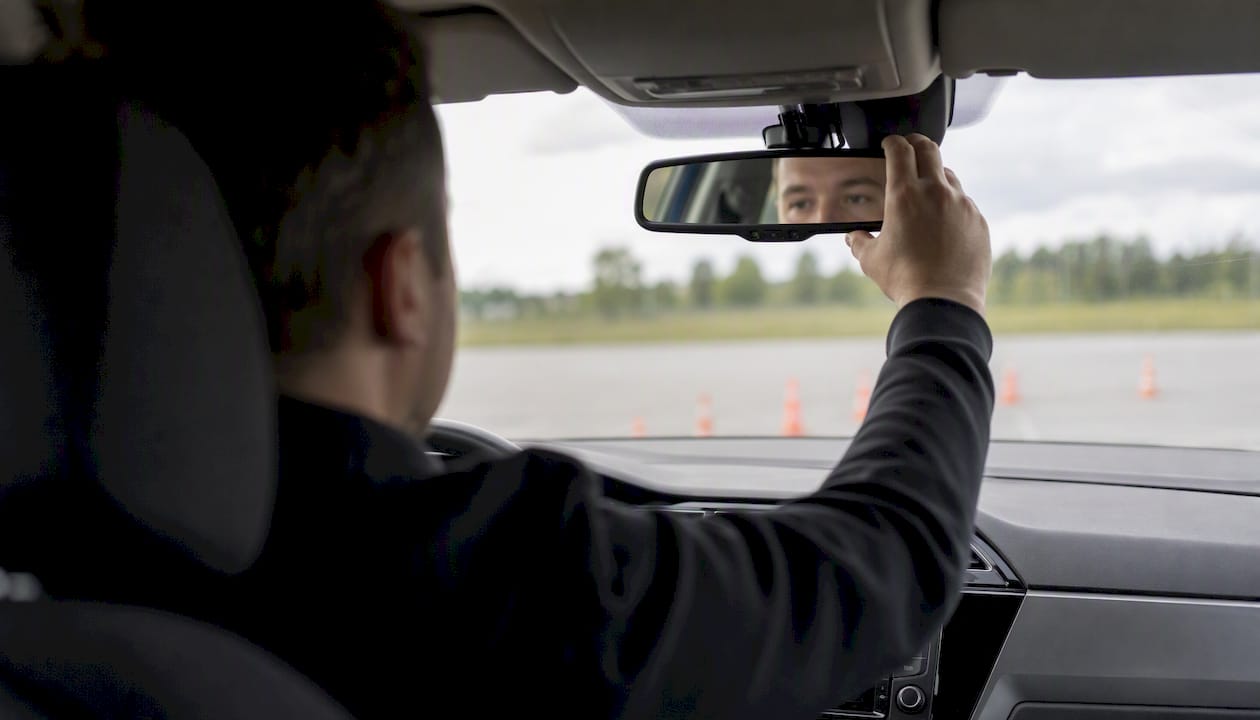 Un élève conducteur règle le rétroviseur dans une voiture d’auto-école.
