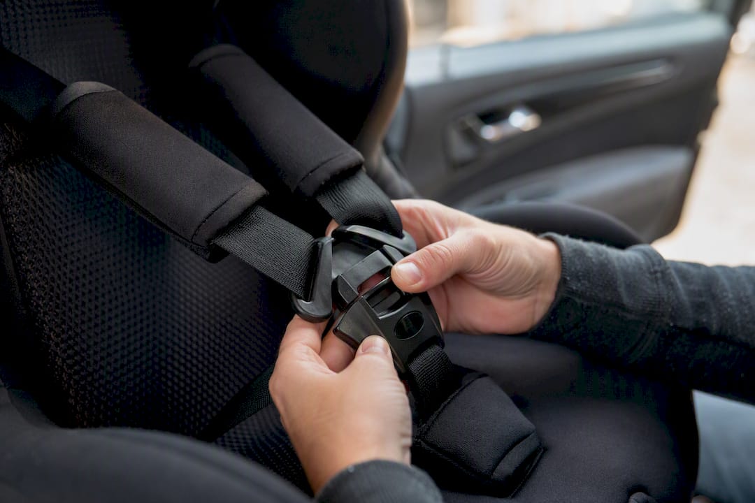 Mains bouclant la sangle d'un siège auto pour enfant