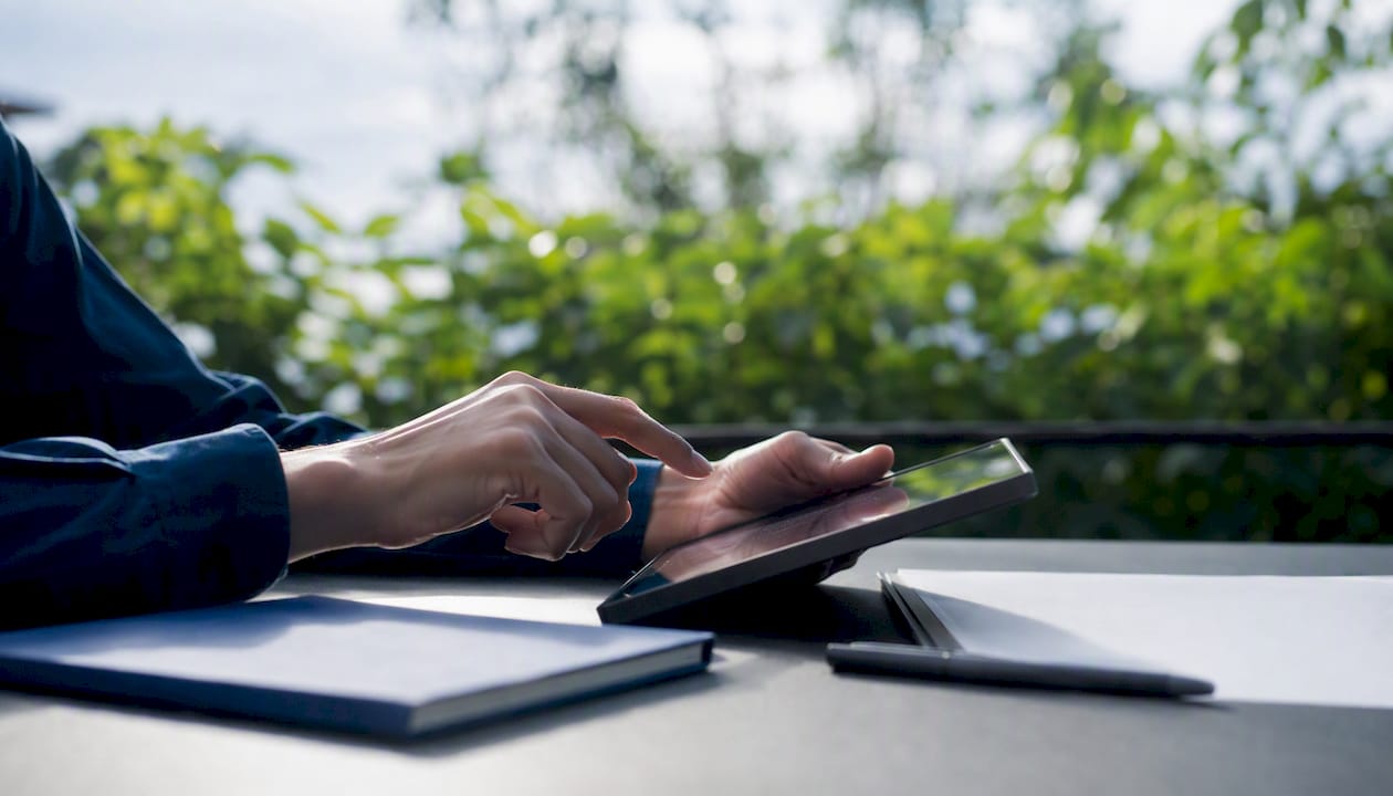 Hands using calculator on desk outdoors