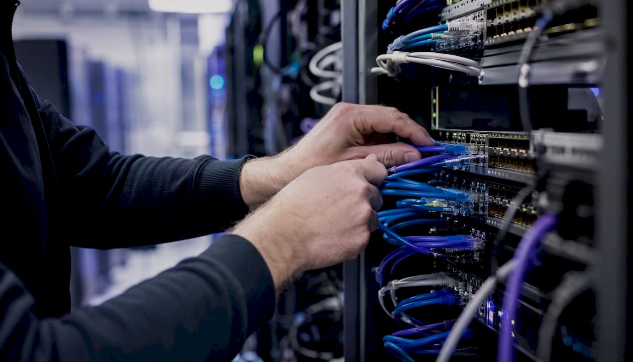 Hands organizing network cables in server room