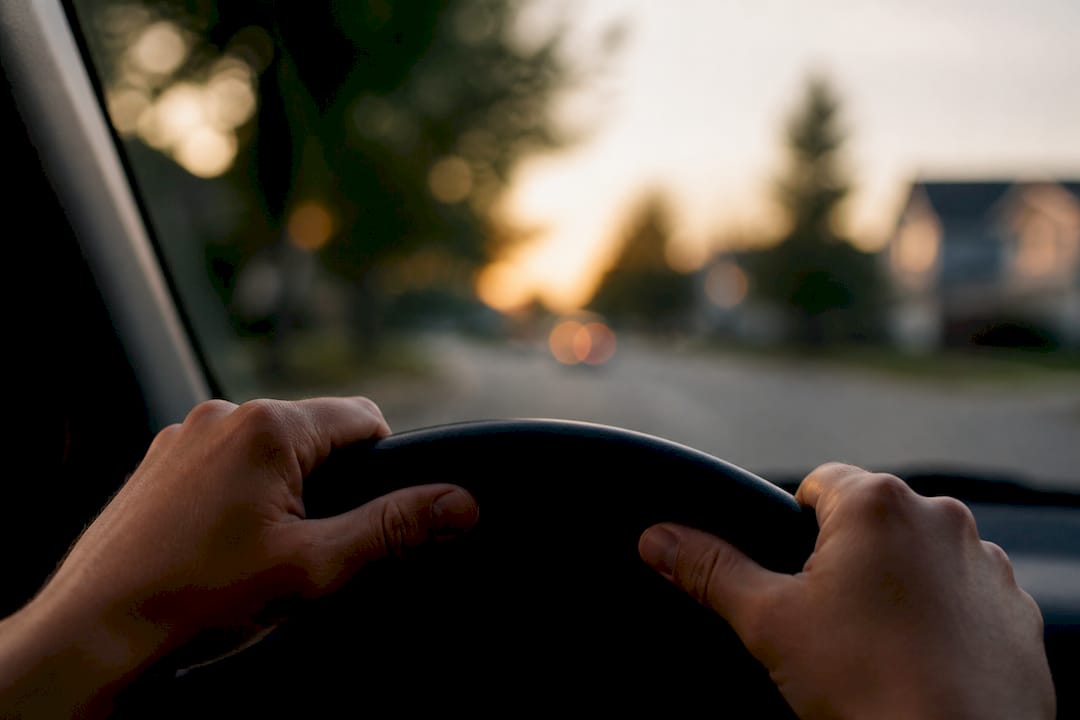 Hands holding car steering wheel driving