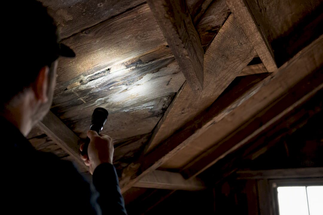 Hand inspecting roof underside with flashlight
