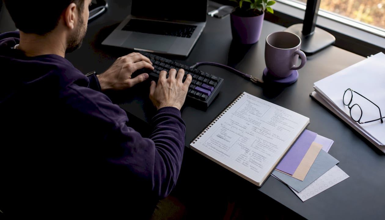 Developer hands typing with code notes and laptop