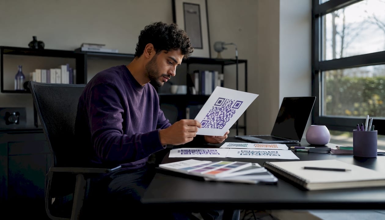 Person examining colored QR code printouts