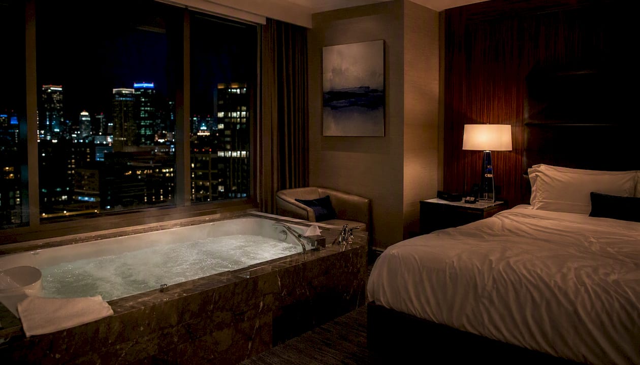 Luxury hotel jacuzzi suite tub with evening city view