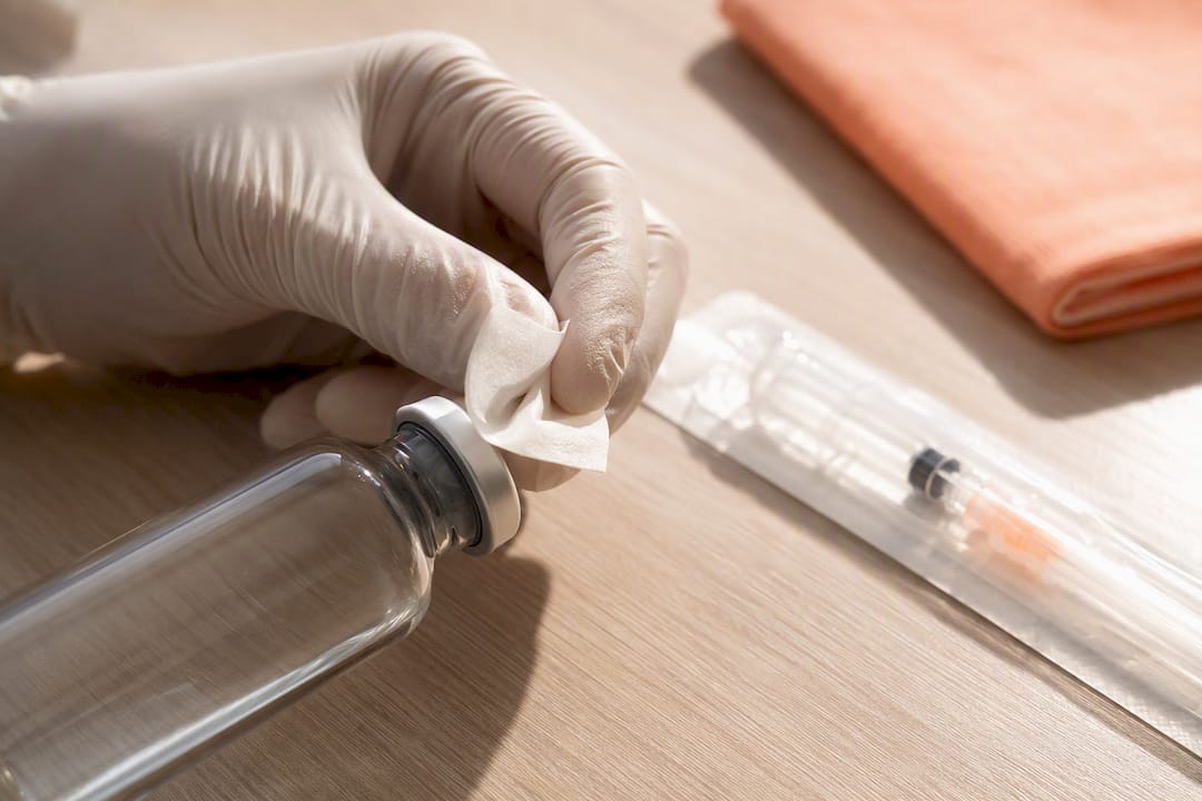 Clinician swabbing an injection vial stopper