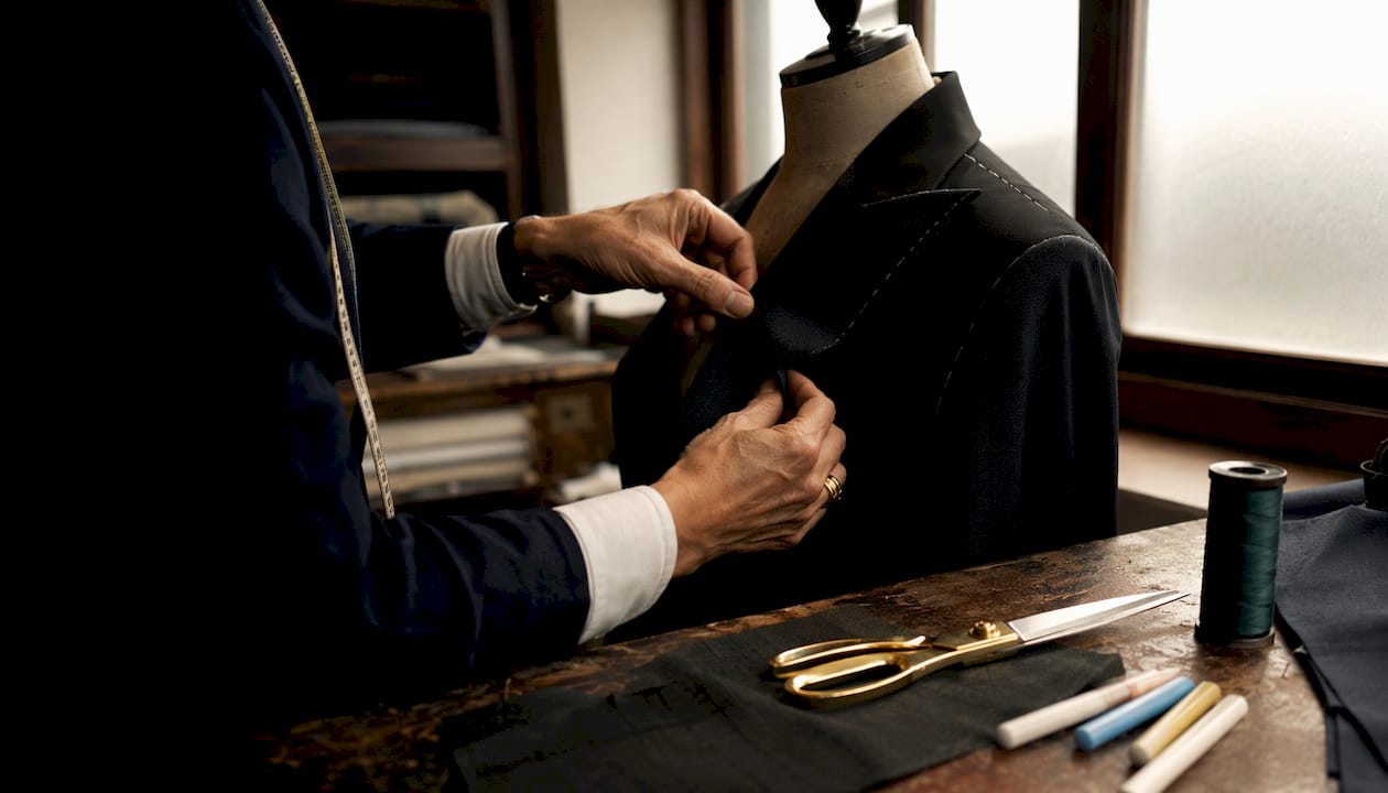 Tailor pinning fabric on tuxedo jacket