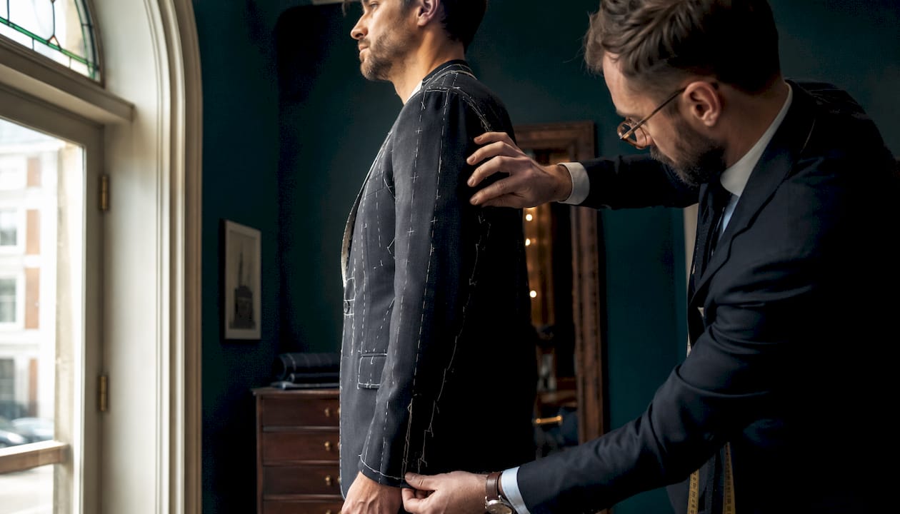 Tailor inspecting shoulder seam on basted suit