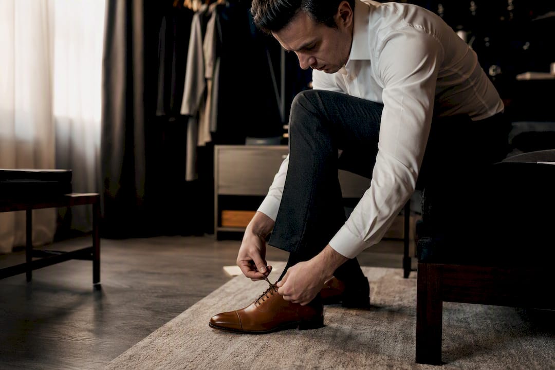 Man tying polished brown oxford shoes