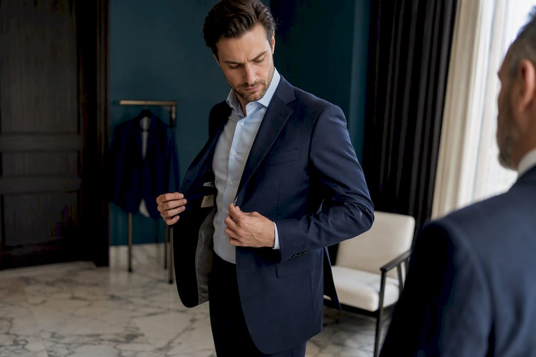 Groom wearing suit adjusting fit in mirror