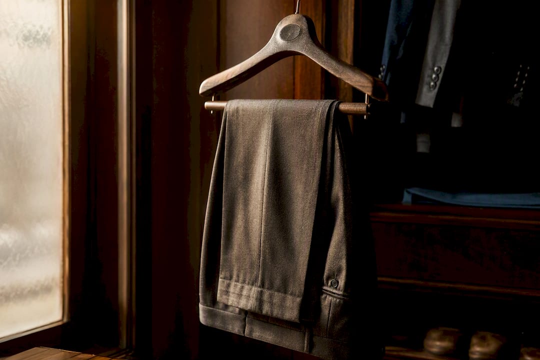 Tailored trousers hanging on wooden hanger