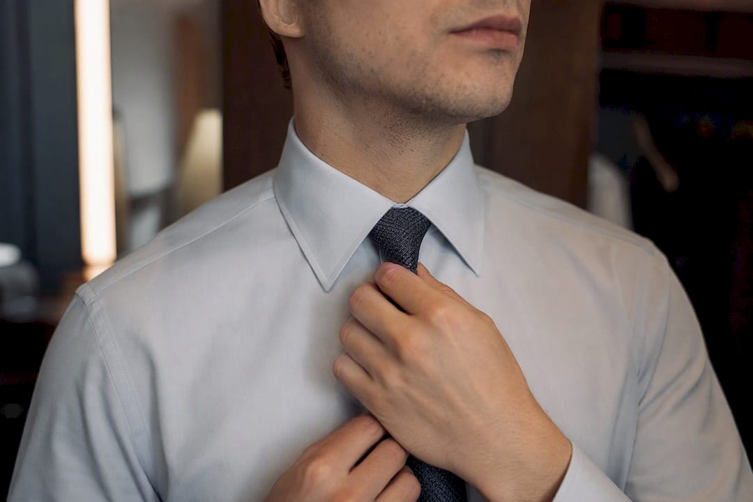 Man adjusting point collar shirt with slim tie knot