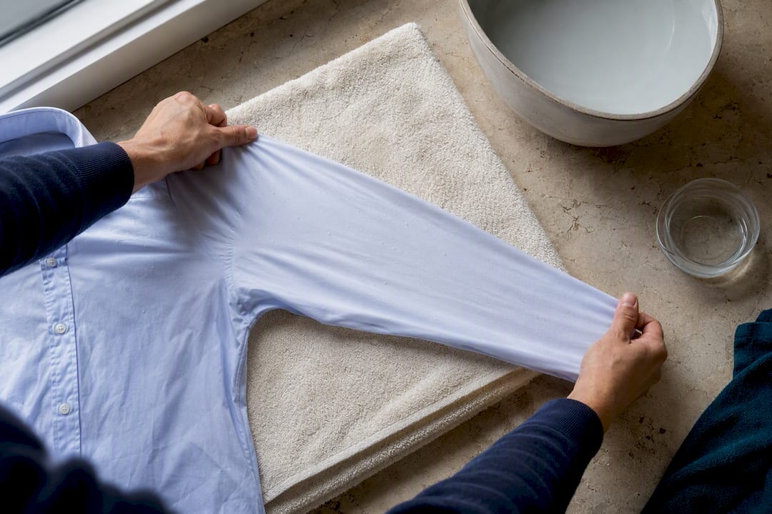 Hands gently reshaping damp shirt fabric
