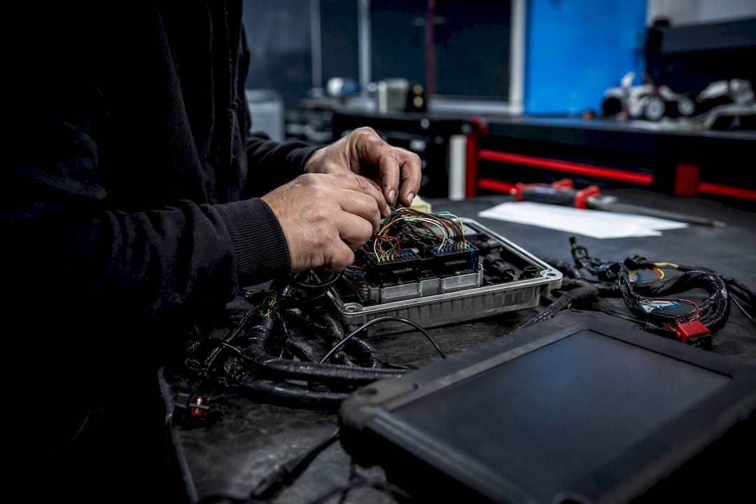 Hands adjusting ECU wiring harness on workshop bench