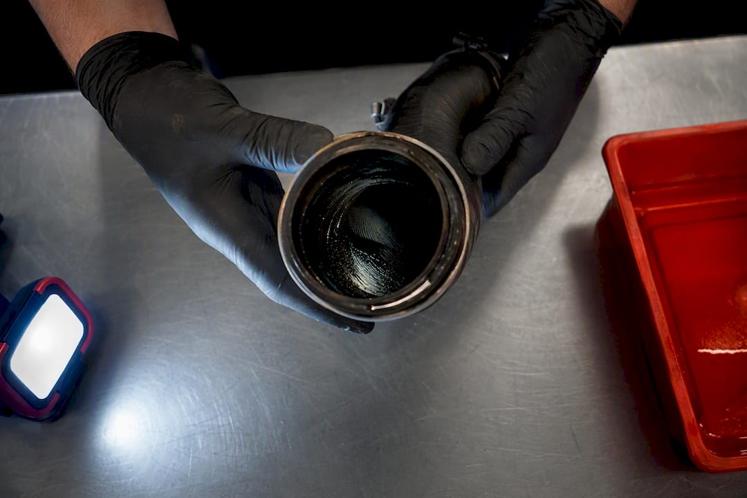 Technician inspecting oil inside intercooler hose