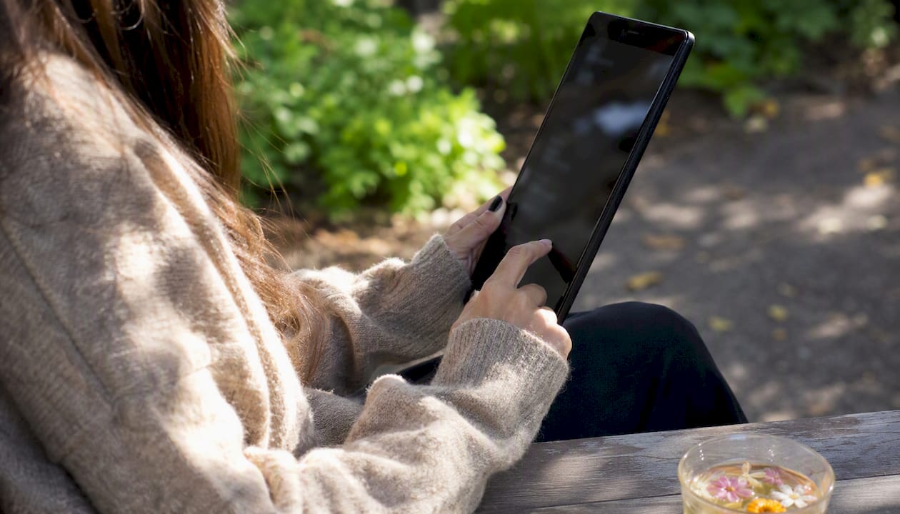 Hands scrolling podcast playlist on tablet