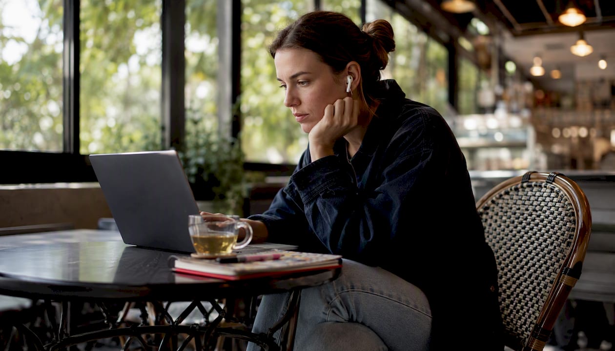 Woman listening to podcasts on laptop at home