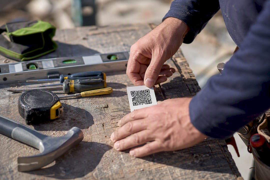 Hands organizing trade tools and QR code on bench