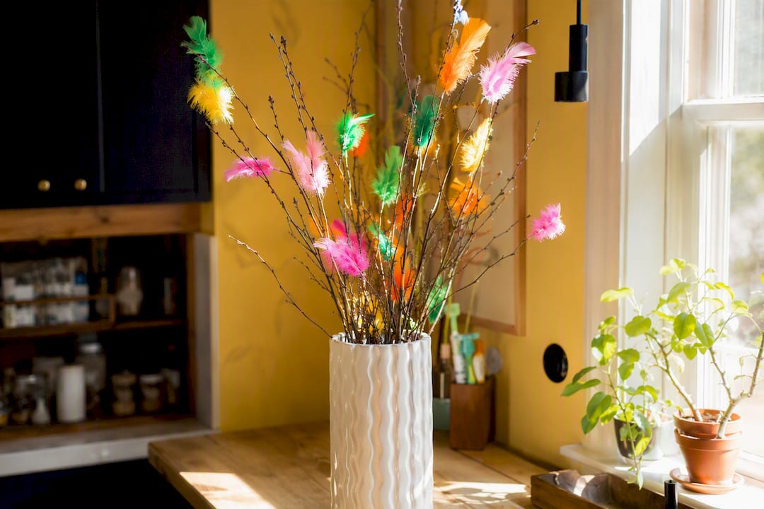 Colorful feather-decorated birch twigs in vase