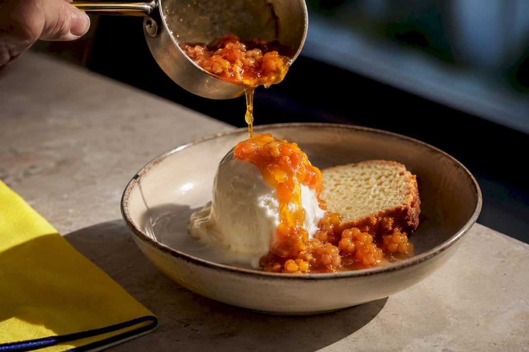 Warm cloudberry jam over vanilla ice cream