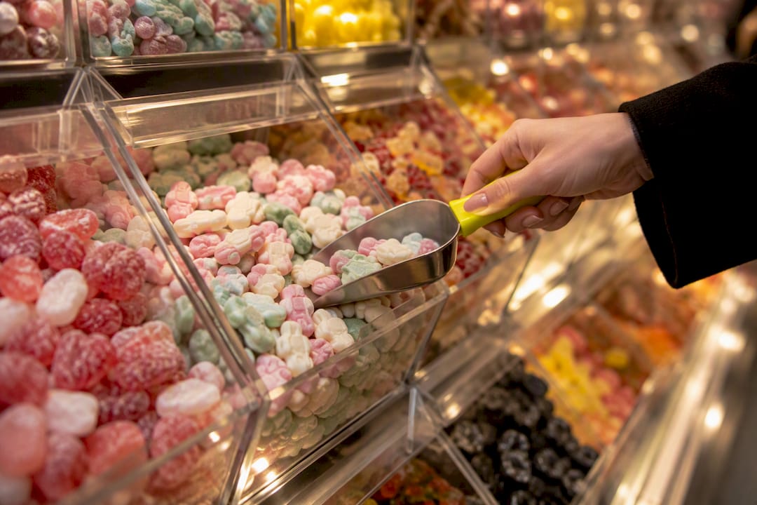 Hand scooping candy from Swedish pick mix wall