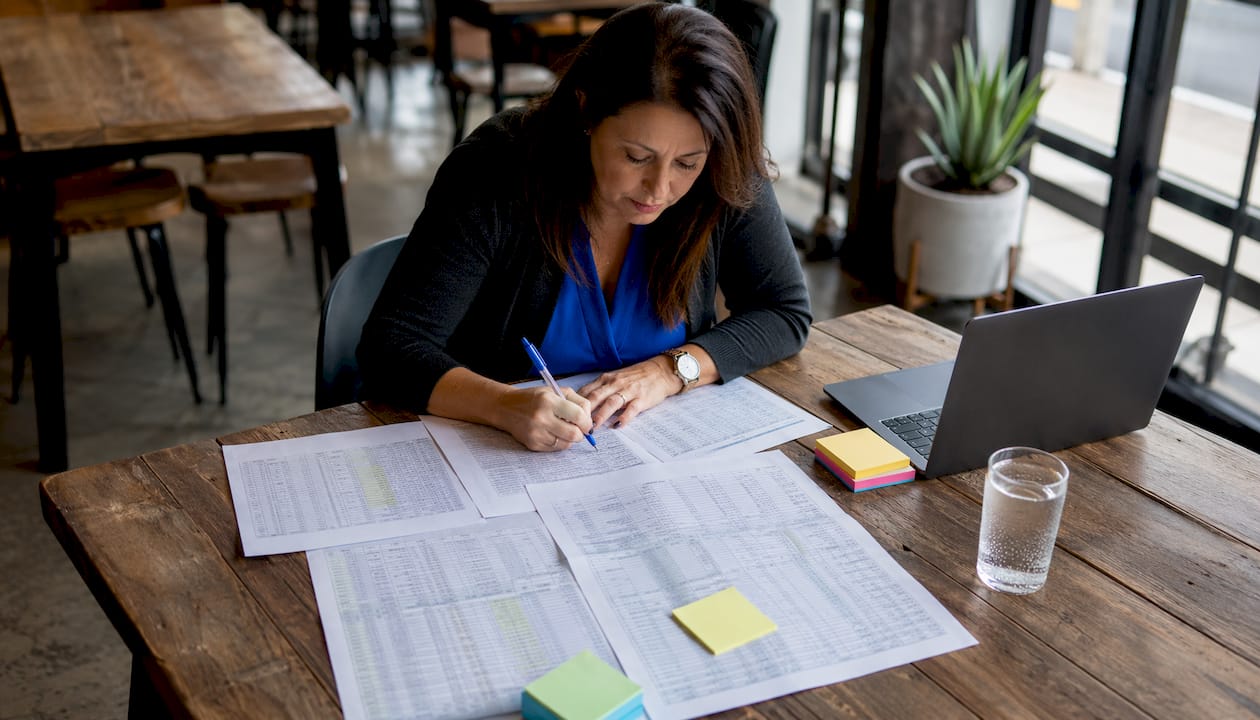 Hands annotating event log documents at home desk