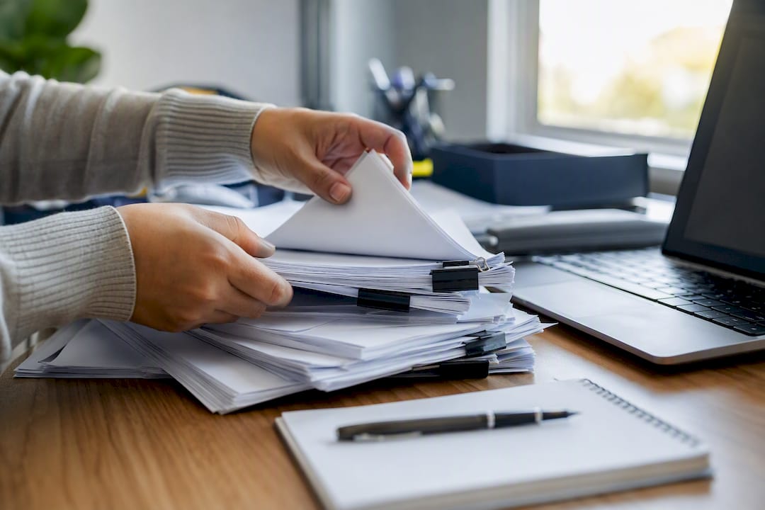 Hands navigating scattered digital devices on office desk