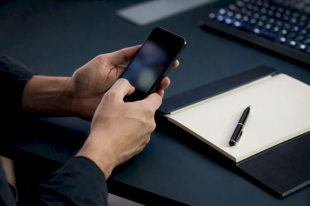 Dłonie obsługujące smartfon podczas pobierania dokumentu
