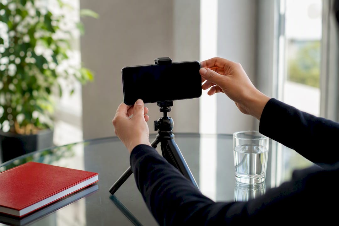 Hands adjusting phone on tripod for video