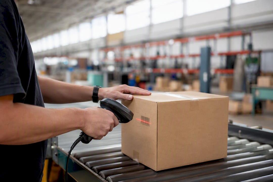 Hands using scanner on package in warehouse