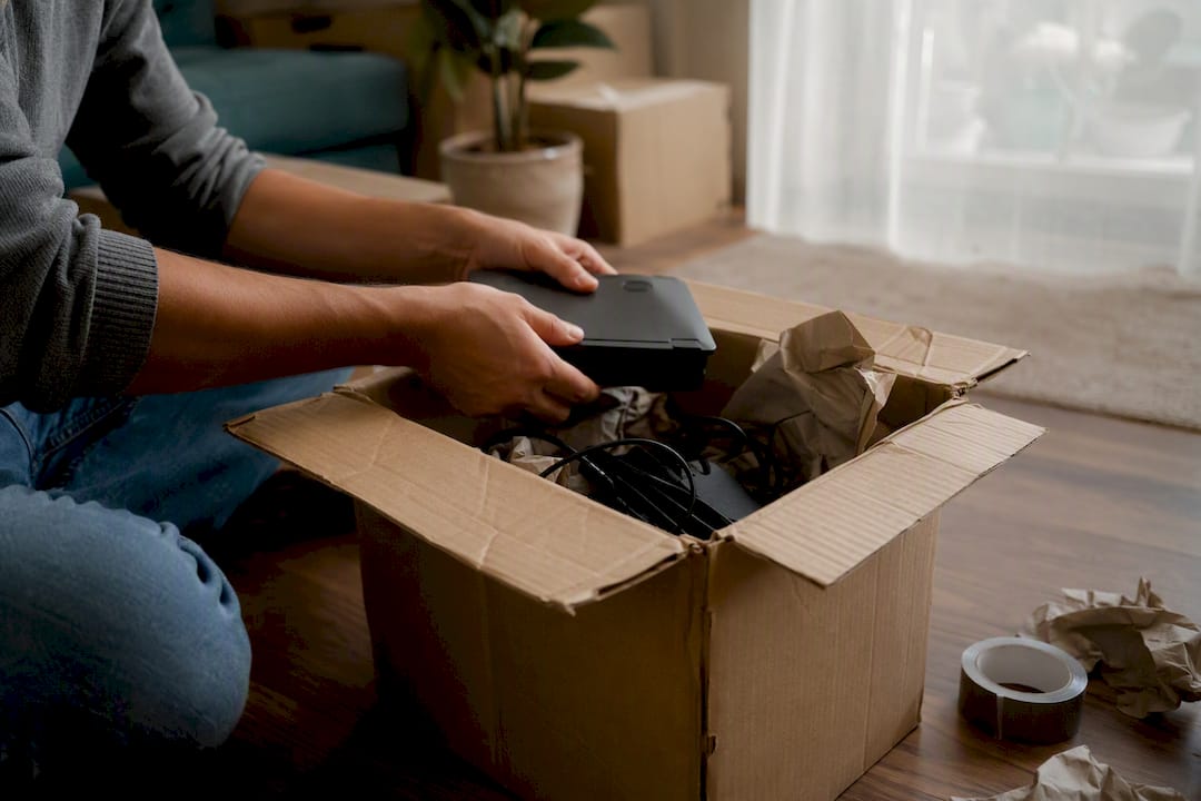 Hands repacking electronics into cardboard box