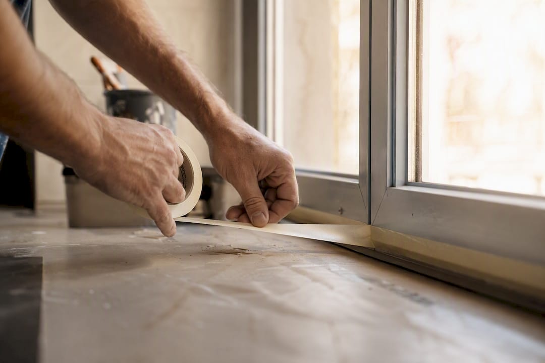 Hands masking aluminium window edges carefully