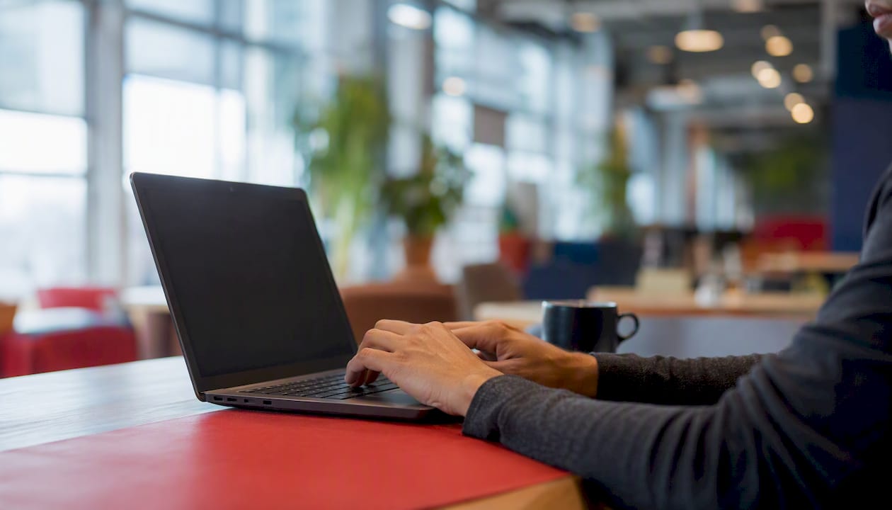 Hands typing on laptop with dark screen