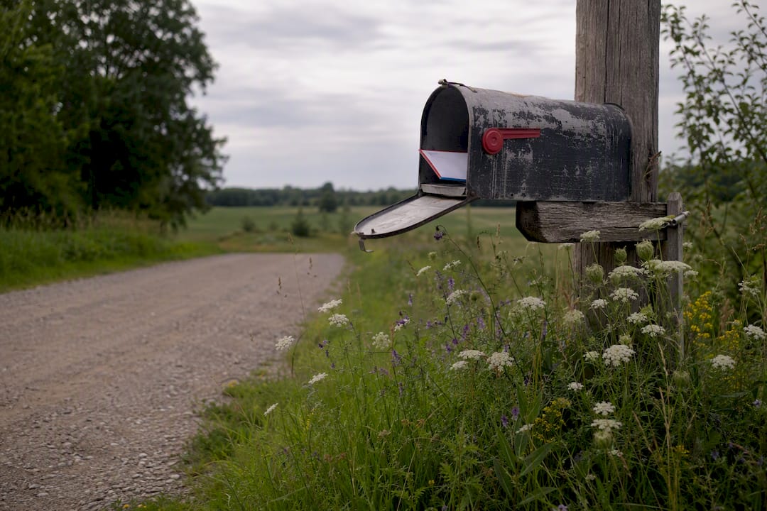 Open rural mailbox with envelope outdoors